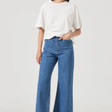 Woman wearing a white top and blue jeans on a white background