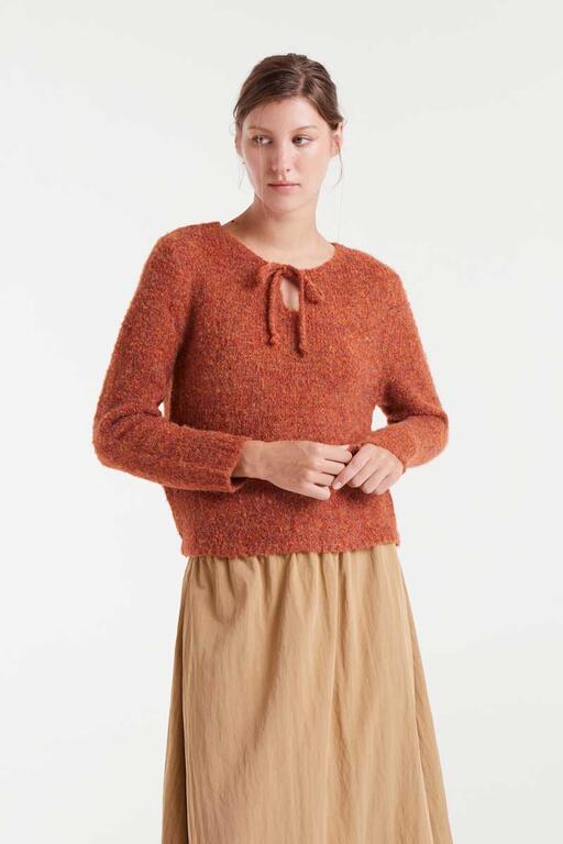 Woman wearing a rust-colored knitted sweater with a white background