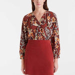 Woman wearing a floral blouse and red skirt on a white background