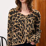 Person wearing a leopard print cardigan in front of a wooden door.