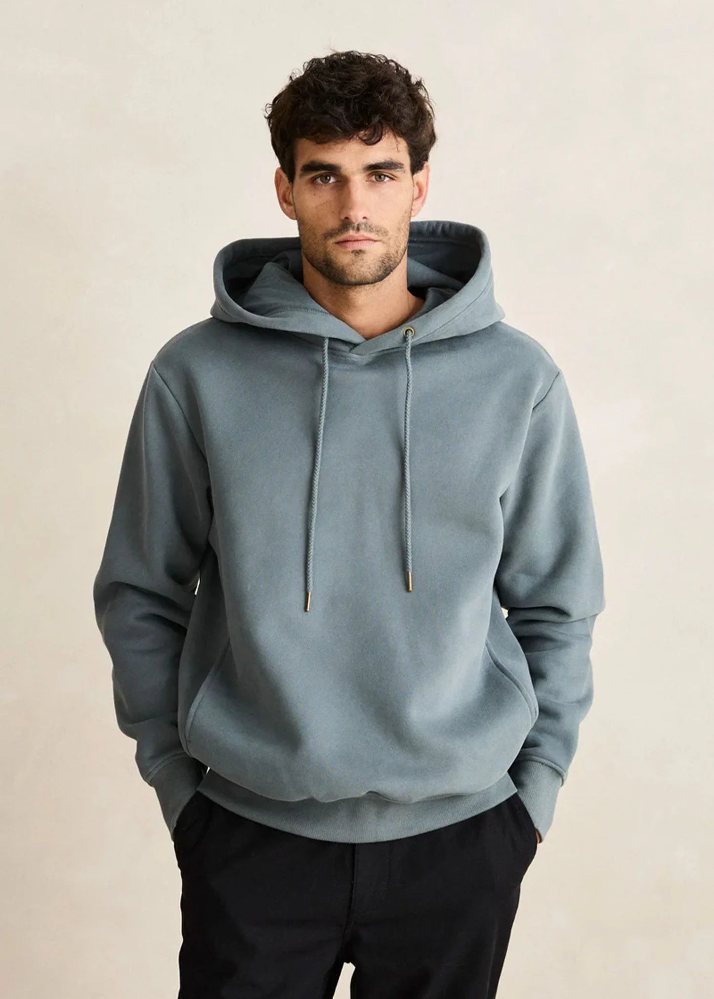 Man wearing a light blue hoodie against a beige background