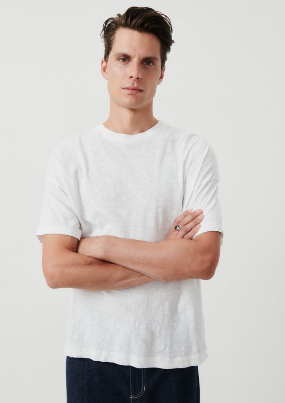 A medium close up headshot image of a male model wearing the Bysapick T-Shirt in white styled with dark denim