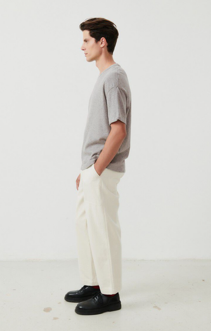 A full body image showing the side of a male model wearing the Sonoma T-shirt in grey styled with cream denim and black shoes