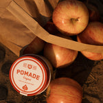 Container of pomade with apples on a rustic background