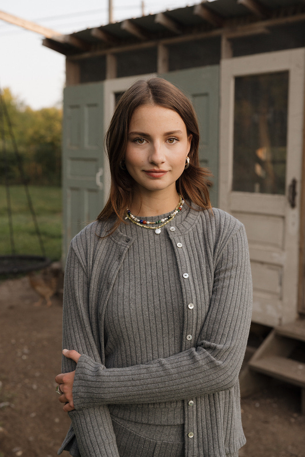 Woman wearing a gray cardigan in front of a green building