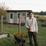 Man standing next to a wheelbarrow with flowers in a garden setting