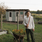 Man standing next to a wheelbarrow with flowers in a garden setting