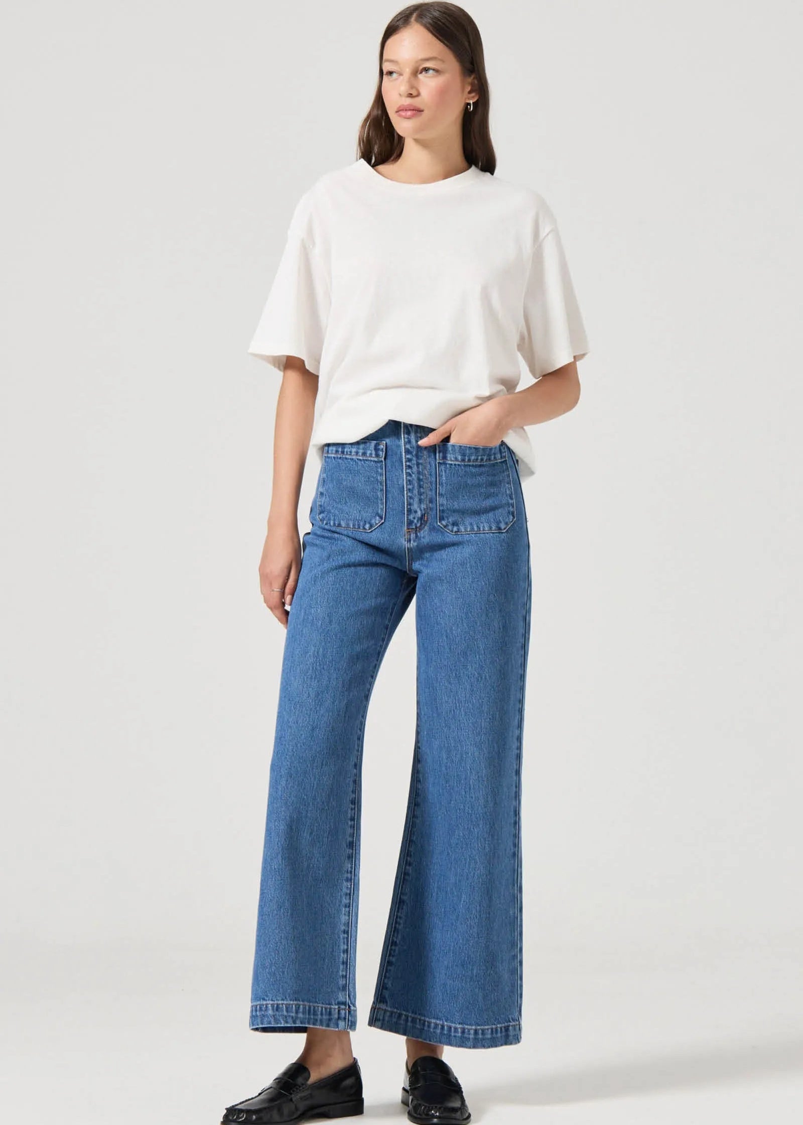 Woman wearing a white top and blue jeans on a white background