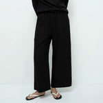 Person wearing black wide-leg pants and a black top on a white background