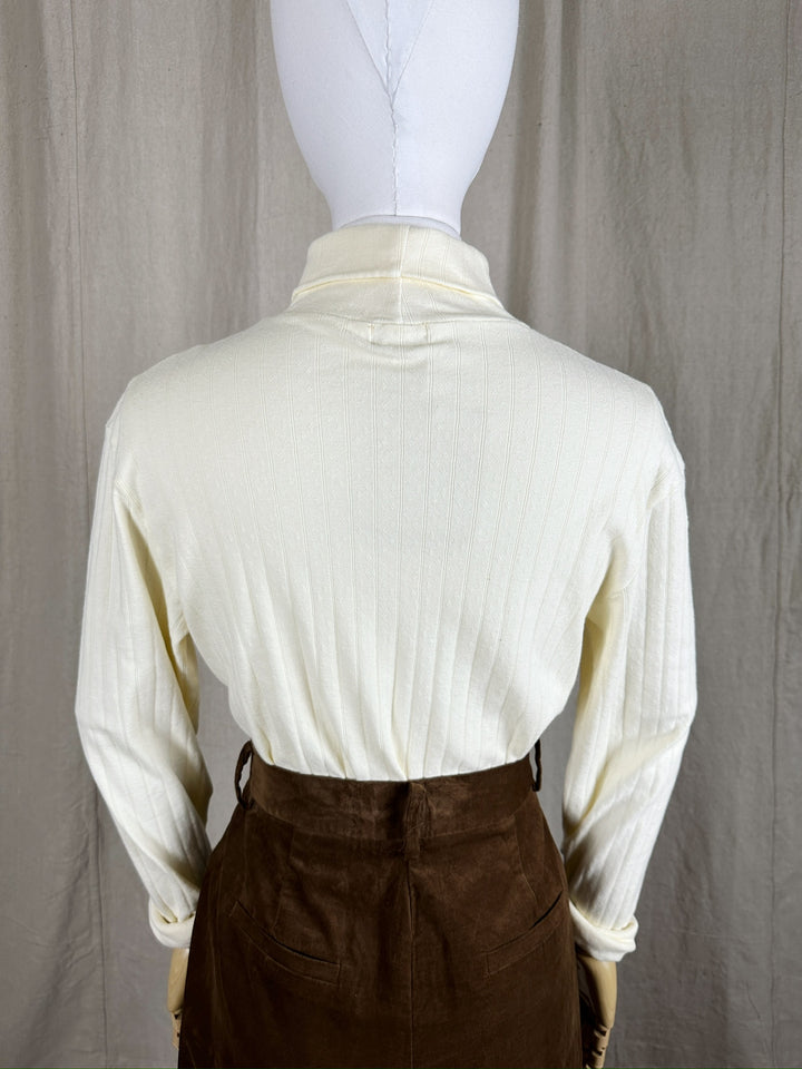 A close up image of the back of the Pointelle Turtleneck styled tucked into a brown pant on a mannequin