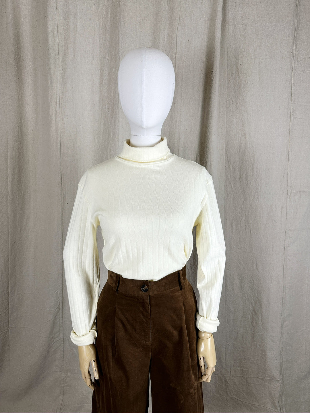 An upper half image showing the Pointelle Turtleneck styled on a mannequin with a wide leg brown pant