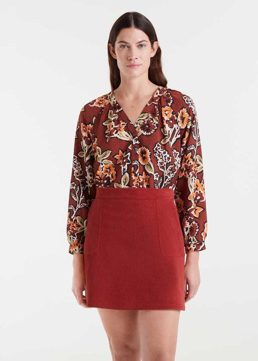 Woman wearing a floral blouse and red skirt on a white background