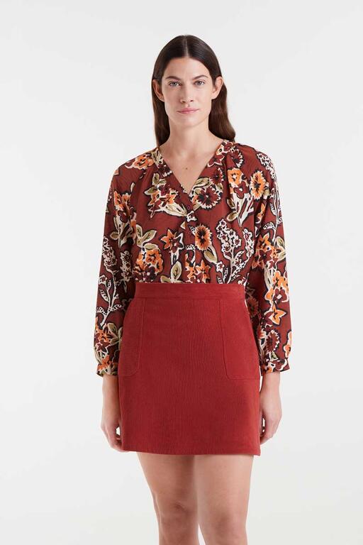 Woman wearing a floral blouse and red skirt on a white background