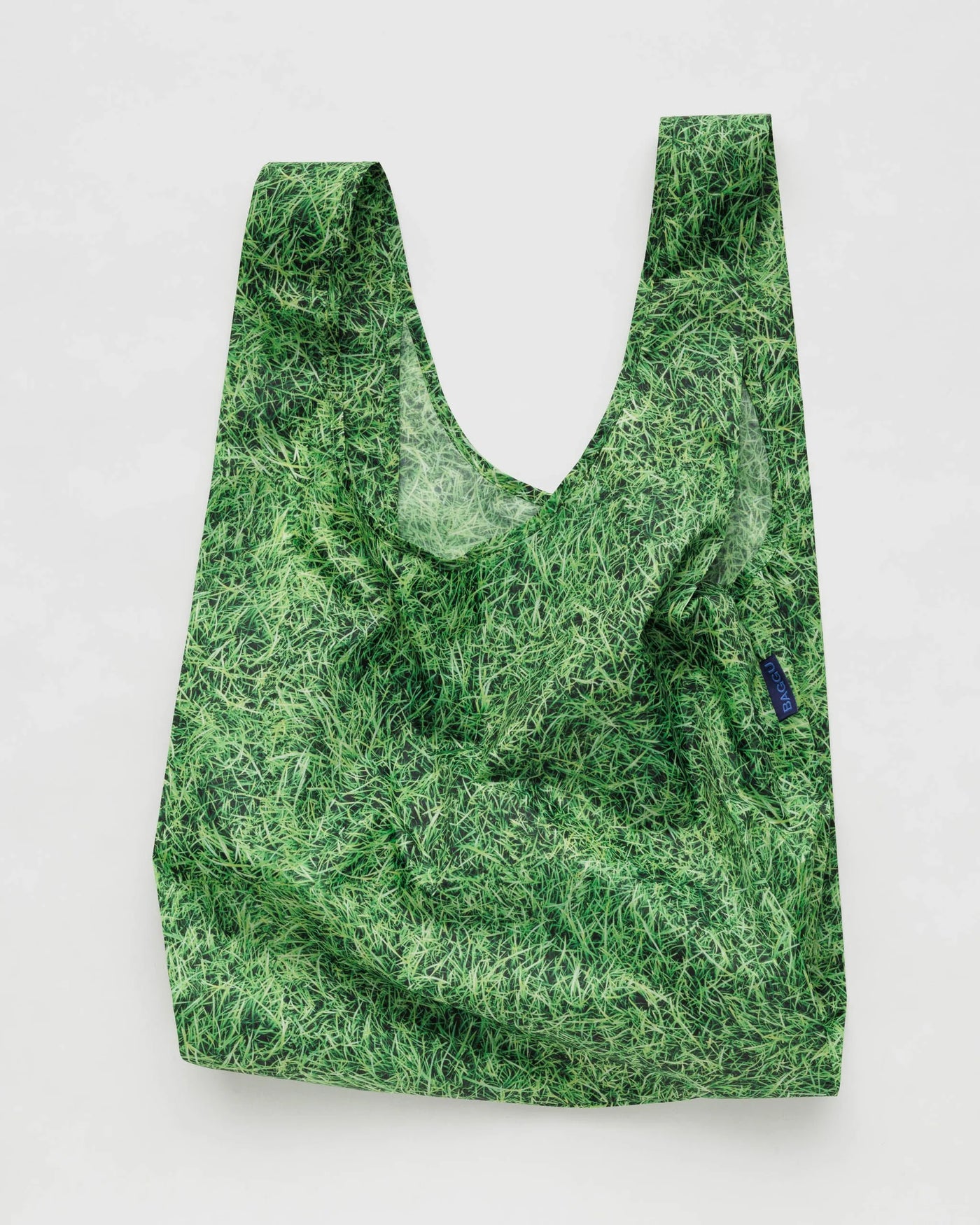 Women wearing a denim shirt and shorts and holding a green grass printed tote bag