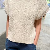 Person wearing a textured beige top and blue shorts indoors.