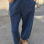 Person wearing blue jeans and a brown top on a street.