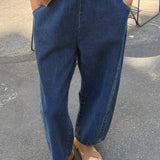 Person wearing blue jeans and a brown top on a street.