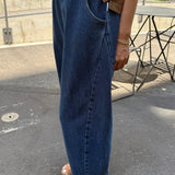 Person wearing blue jeans and a brown top on a street.