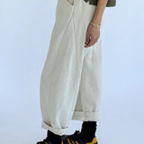 Person wearing beige wide-leg pants, black sneakers with yellow accents, and a grey top on a white background