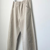 Beige pants hanging on a wooden hanger against a white wall