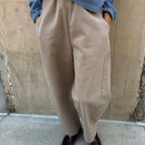Person wearing beige pants and a blue shirt against a beige wall.