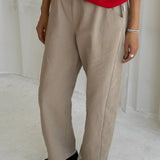 Person wearing beige pants and a red top on a plain background