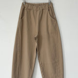 Brown pants hanging on a wooden hanger against a white background