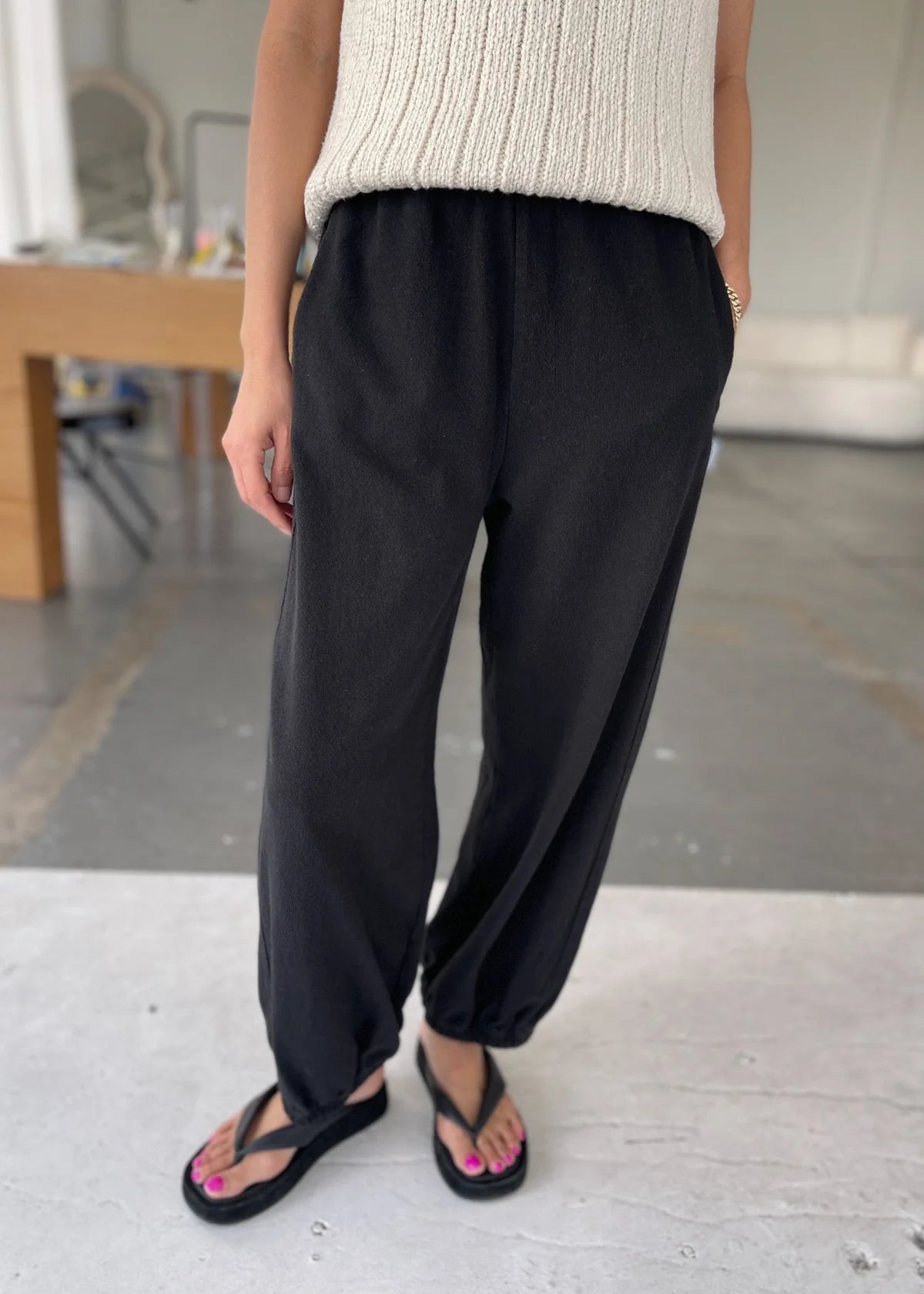 Person wearing black pants and a beige sweater in an indoor setting