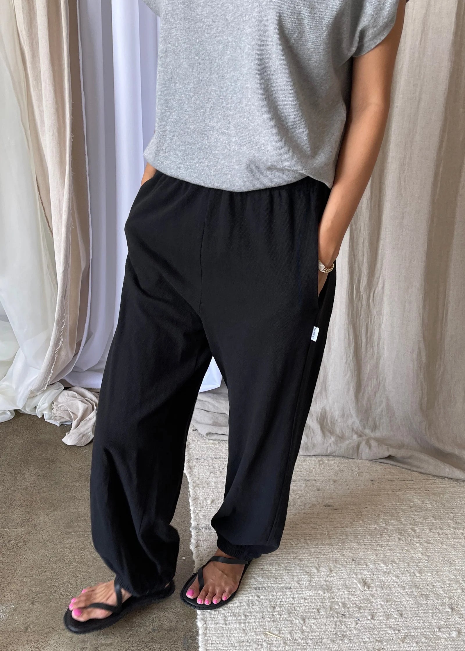 Person wearing black pants and a grey tee shirt in an indoor setting