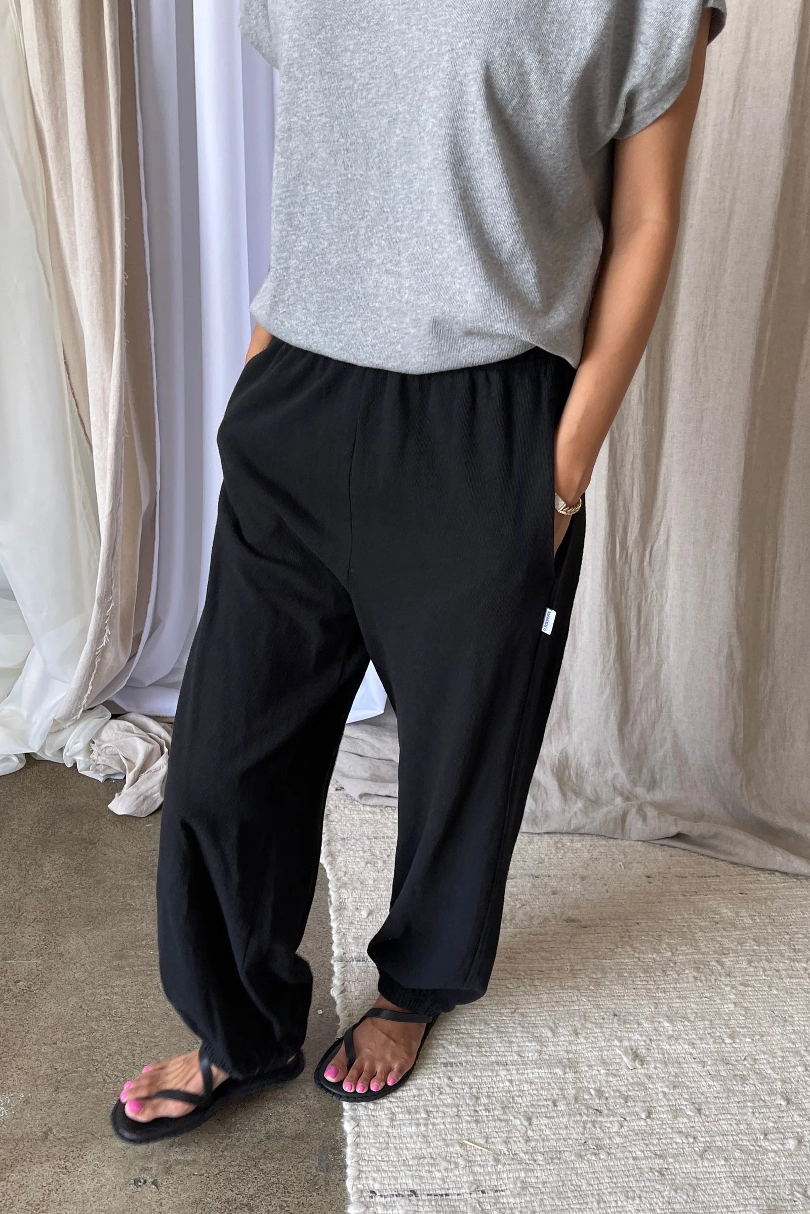 Person wearing black pants and a grey tee shirt in an indoor setting