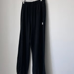 Black knit joggers on  wood hanger hanging from a wood hook.