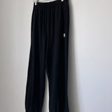 Black knit joggers on  wood hanger hanging from a wood hook.