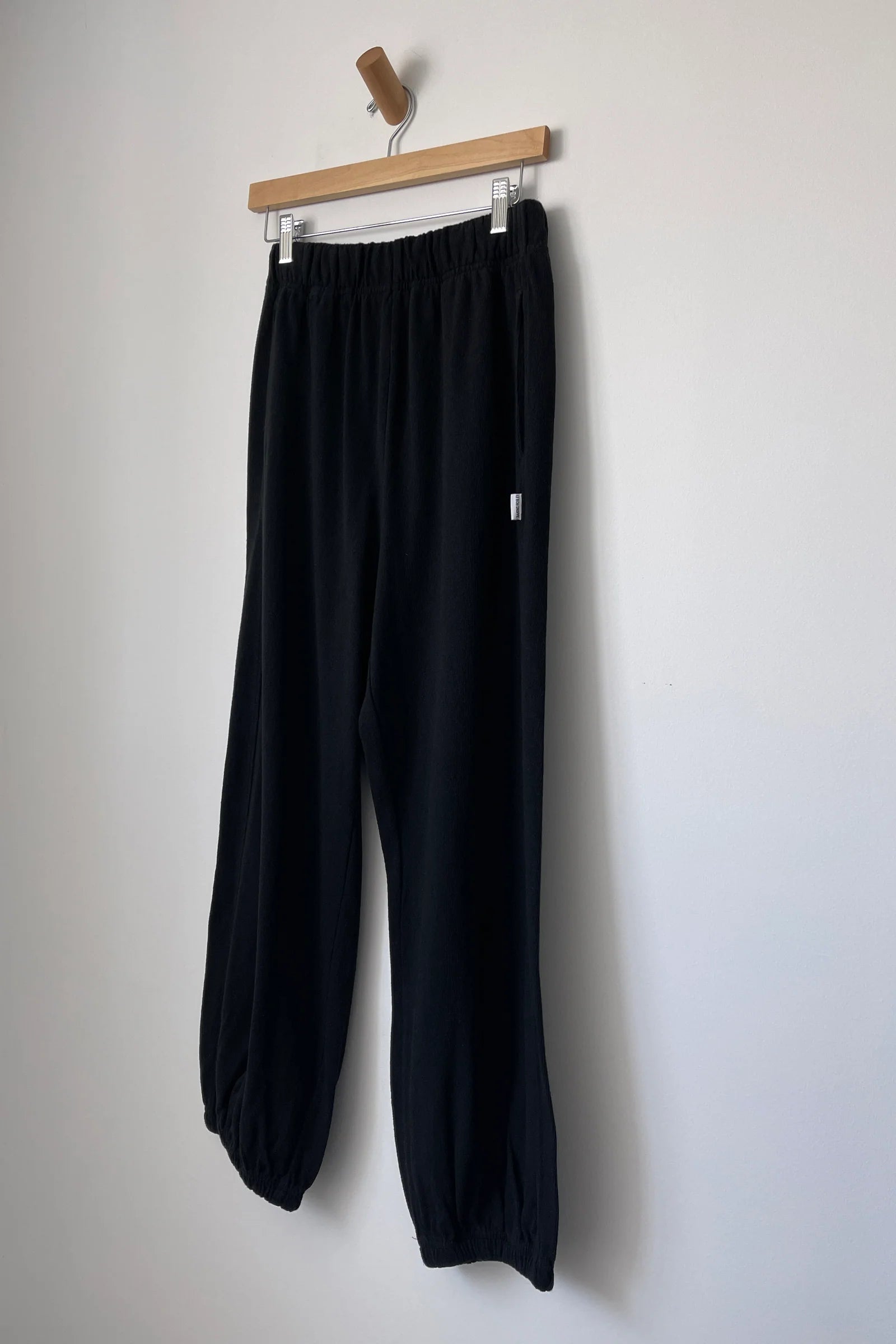 Black knit joggers on  wood hanger hanging from a wood hook.