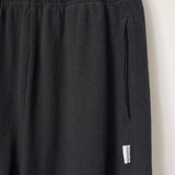Close up of knit black joggers on a hanger.