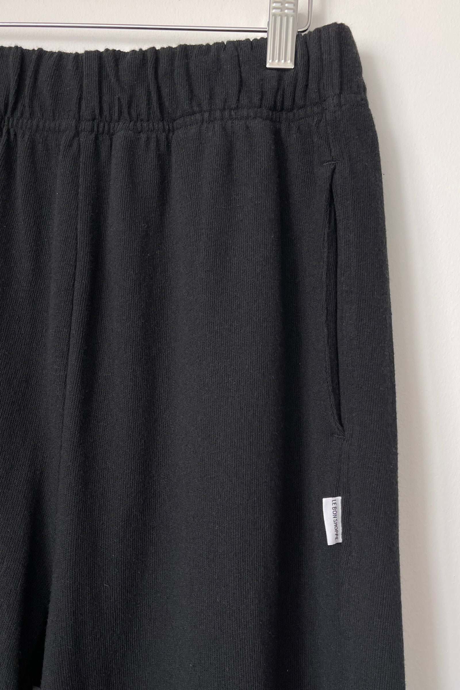 Close up of knit black joggers on a hanger.