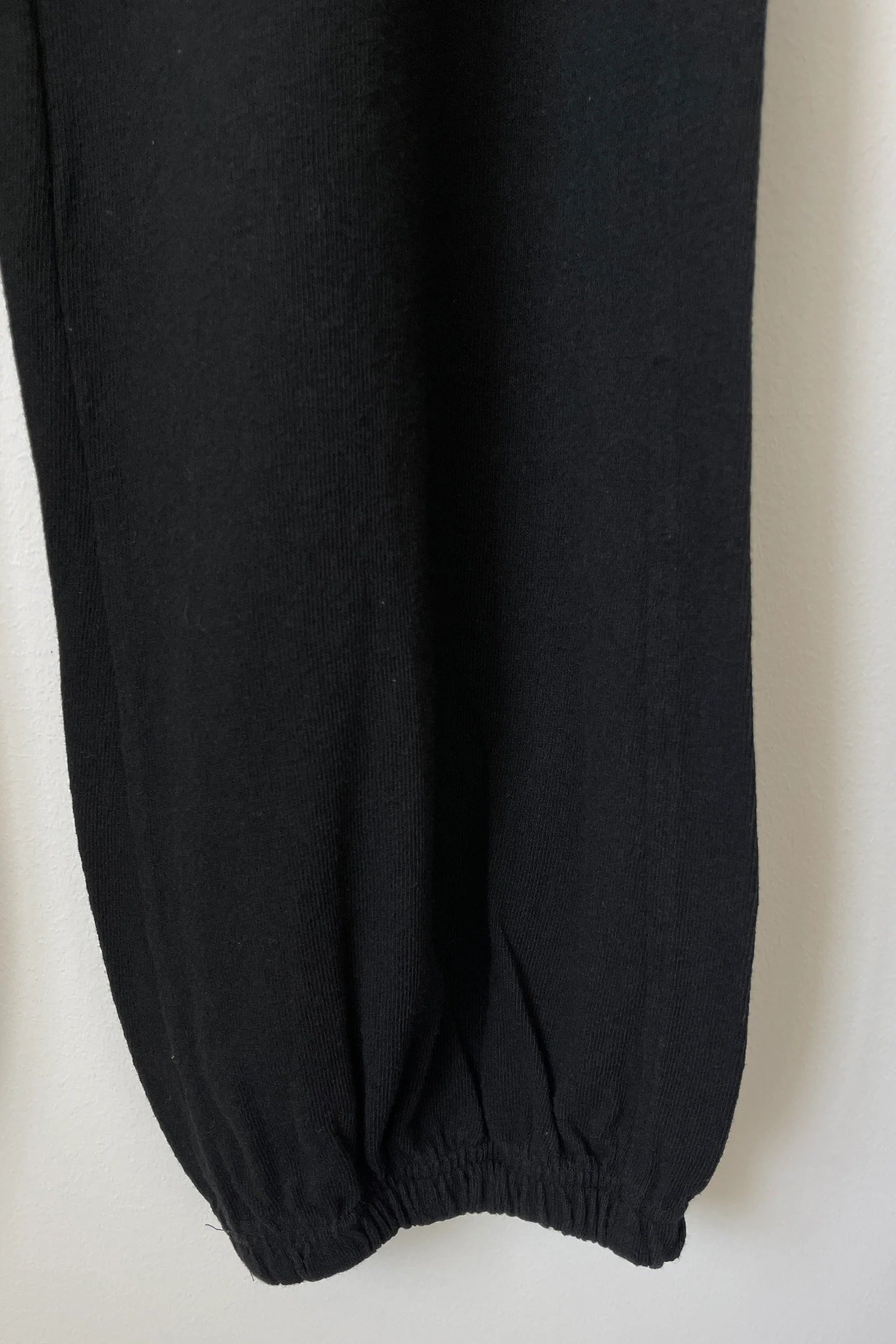 Close up of bottom of leg of black knit joggers.