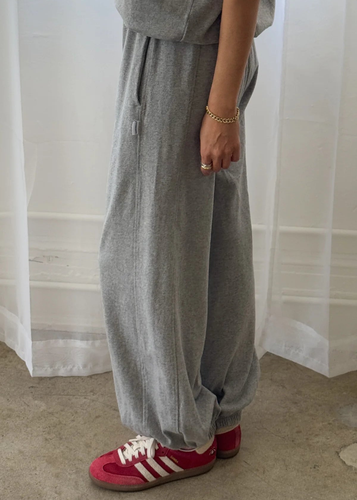 A person wearing gray balloon pants and red sneakers, standing indoors.