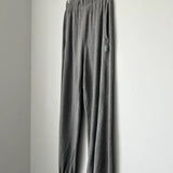 Gray sweatpants hanging on a wooden hanger against a white wall.