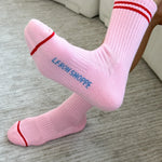 Person wearing pink socks with red stripes on carpet floor.