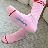Person wearing pink socks with red stripes on carpet floor.