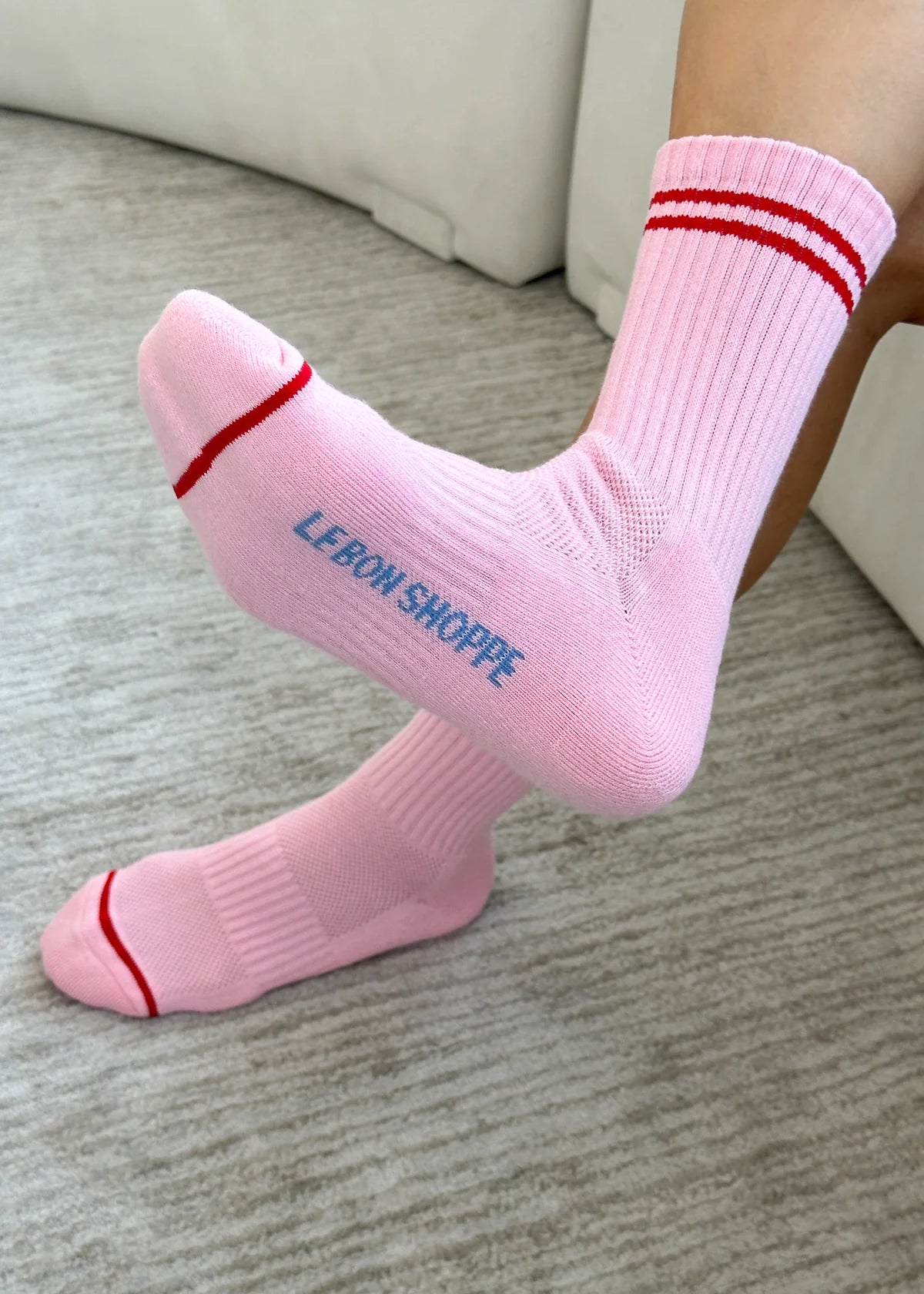 Person wearing pink socks with red stripes on carpet floor.