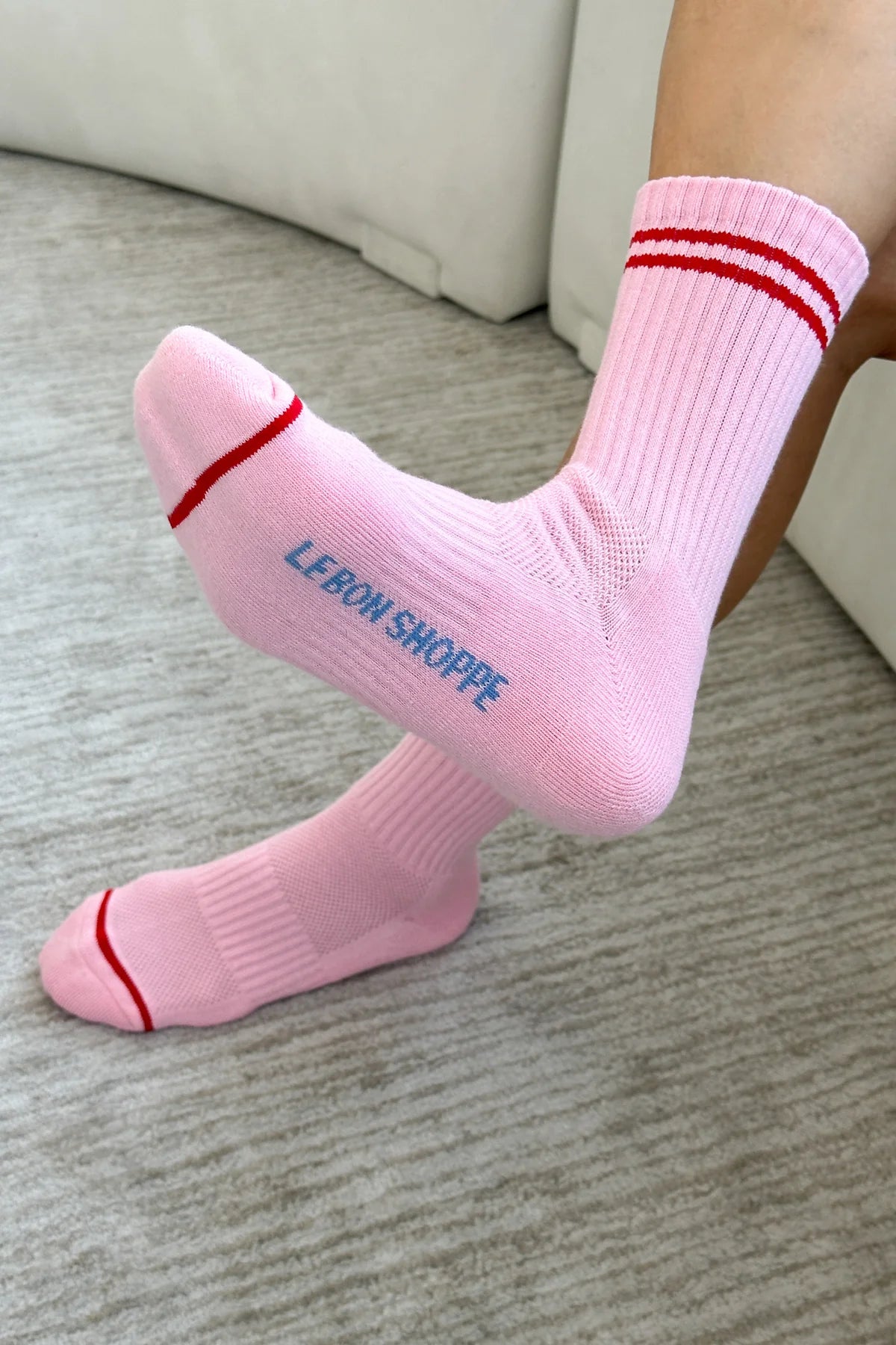 Person wearing pink socks with red stripes on carpet floor.