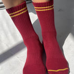 Red socks with yellow stripes worn by a person on a light gray surface