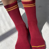 Red socks with yellow stripes worn by a person on a light gray surface