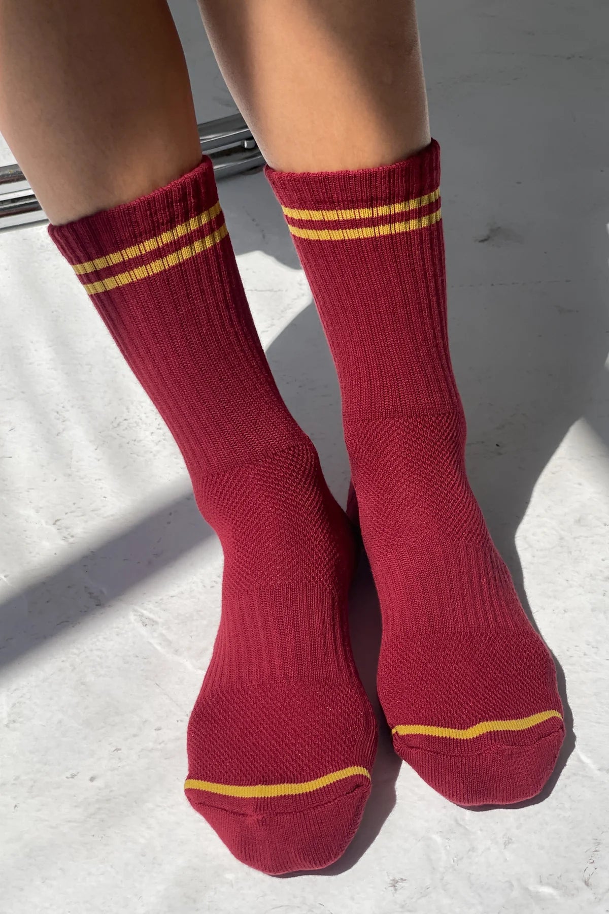Red socks with yellow stripes worn by a person on a light gray surface