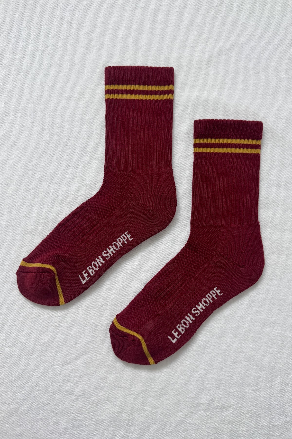 Maroon socks with gold stripes on a white bavkground.