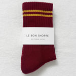 Maroon socks with yellow stripes on a white background, in Le Bon Shoppe packaging.