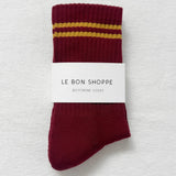 Maroon socks with yellow stripes on a white background, in Le Bon Shoppe packaging.