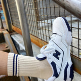 White and navy sneaker with a matching sock on a metal staircase.