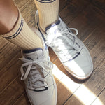 White sneakers with beige socks on a wooden floor